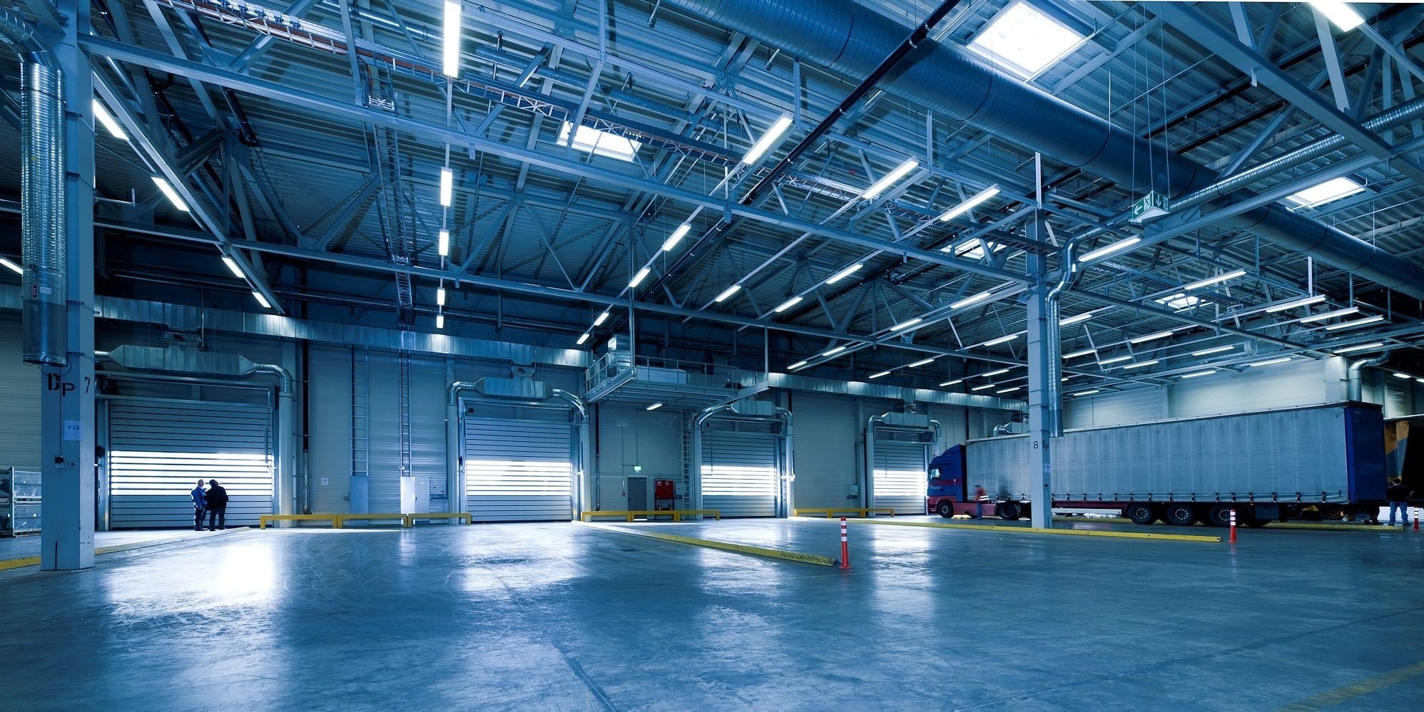 empty-warehouse-min Image of a warehouse with four warehouse doors and truck in the last bay.
